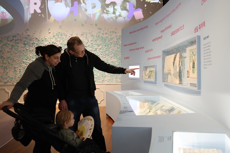 ▲ 7일 서울 종로구 국립민속박물관에서 열린 특별전 ‘출산, 모두의 잔치’를 찾은 외국인 가족이 아기띠의 과거와 현재 모습을 살펴보고 있다. 한국은 전통적으로 커다란 누비천에 긴 끈이 달린 '포대기'를 사용해 아기를 등에 업는 ‘어부바’ 문화가 발달했다. 서양에서는 주로 아기를 앞으로 안지만, 한국의 전통 육아 방식은 엄마와 아이의 밀착감을 높여주는 독특한 특징이 있다. A family on April 7 looks at past and present baby carriers at the exhibition “Happy Birthday” at the National Folk Museum of Korea in Seoul. Traditionally, Koreans use podaegi, a quilted cloth with long straps, to carry babies on their backs — unlike in Western cultures where babies are usually carried in the front — enhancing close physical bonding between mother and child.